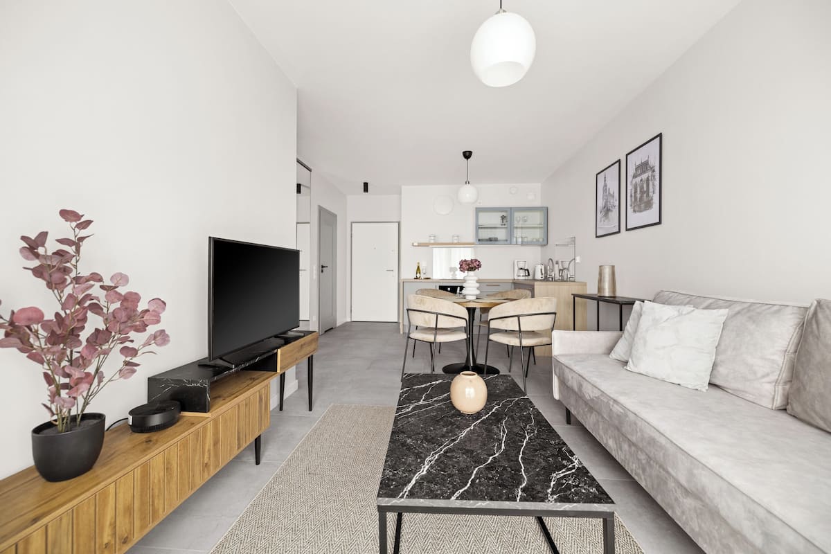 A modern living room with a TV, sofa, dining area, and kitchen.
