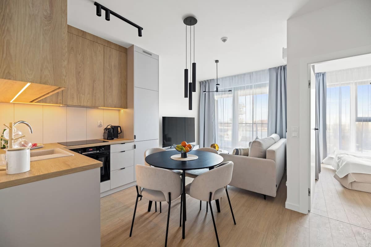 A modern kitchen with a dining area, a sofa, and a TV.
