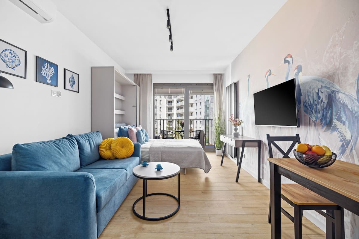 A modern living room with a sofa, a round table, and a TV on a wall.