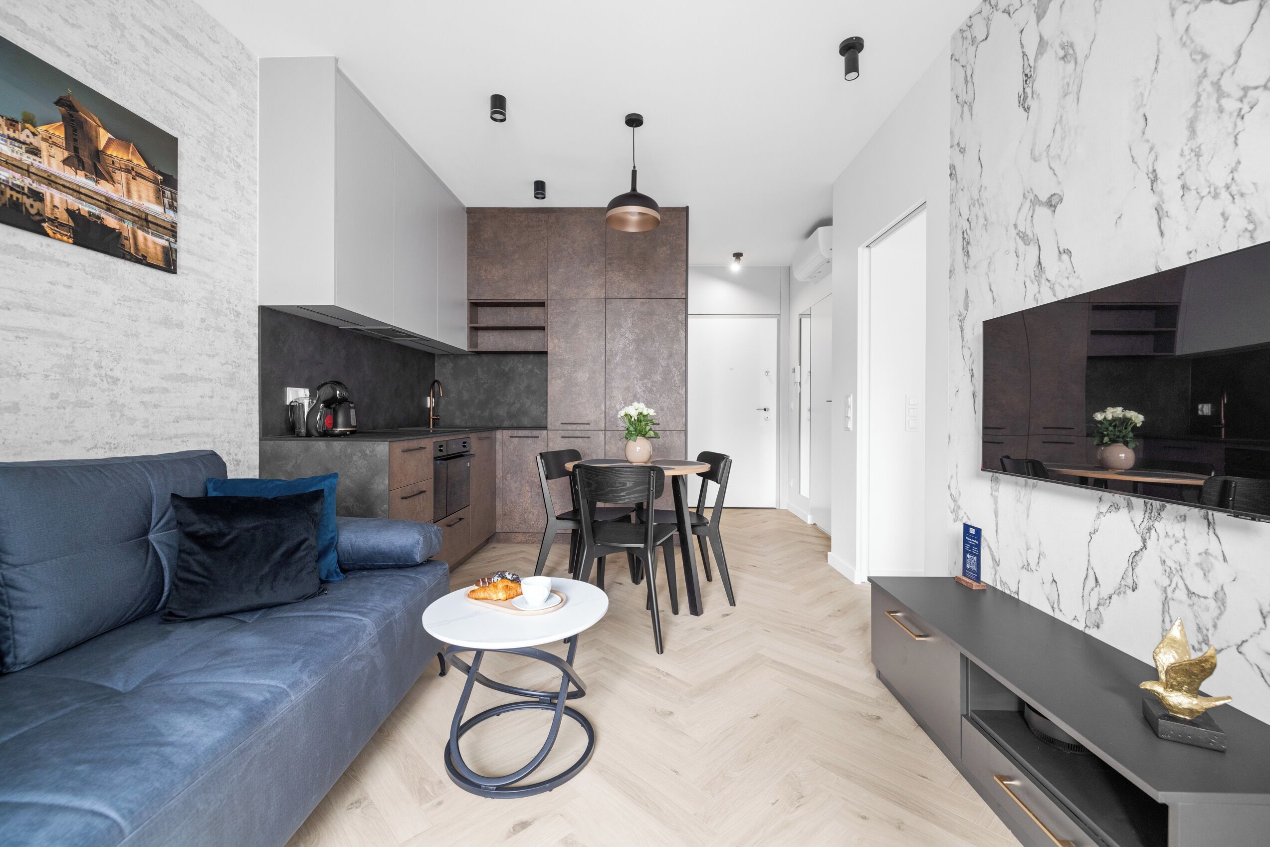 A modern living space with a sofa, dining table, and kitchen area.
