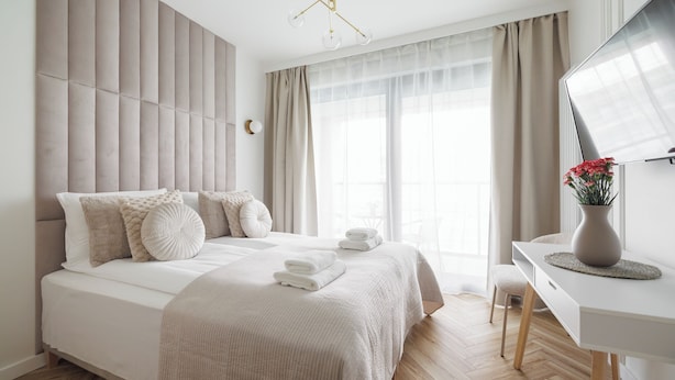 A modern bedroom with a large bed, a desk, and a chair. - City Break Żurawie Aparthotel  (Gdansk)