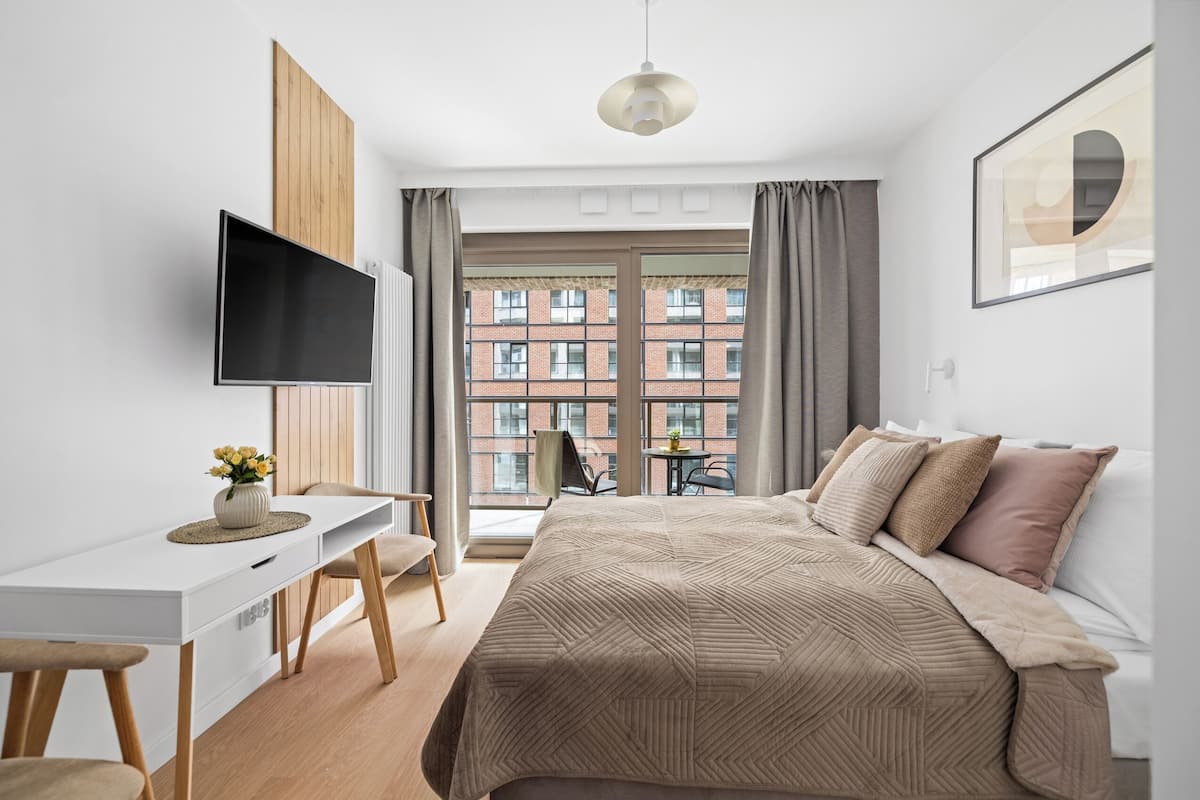 A modern bedroom with a bed, a desk, and a TV.