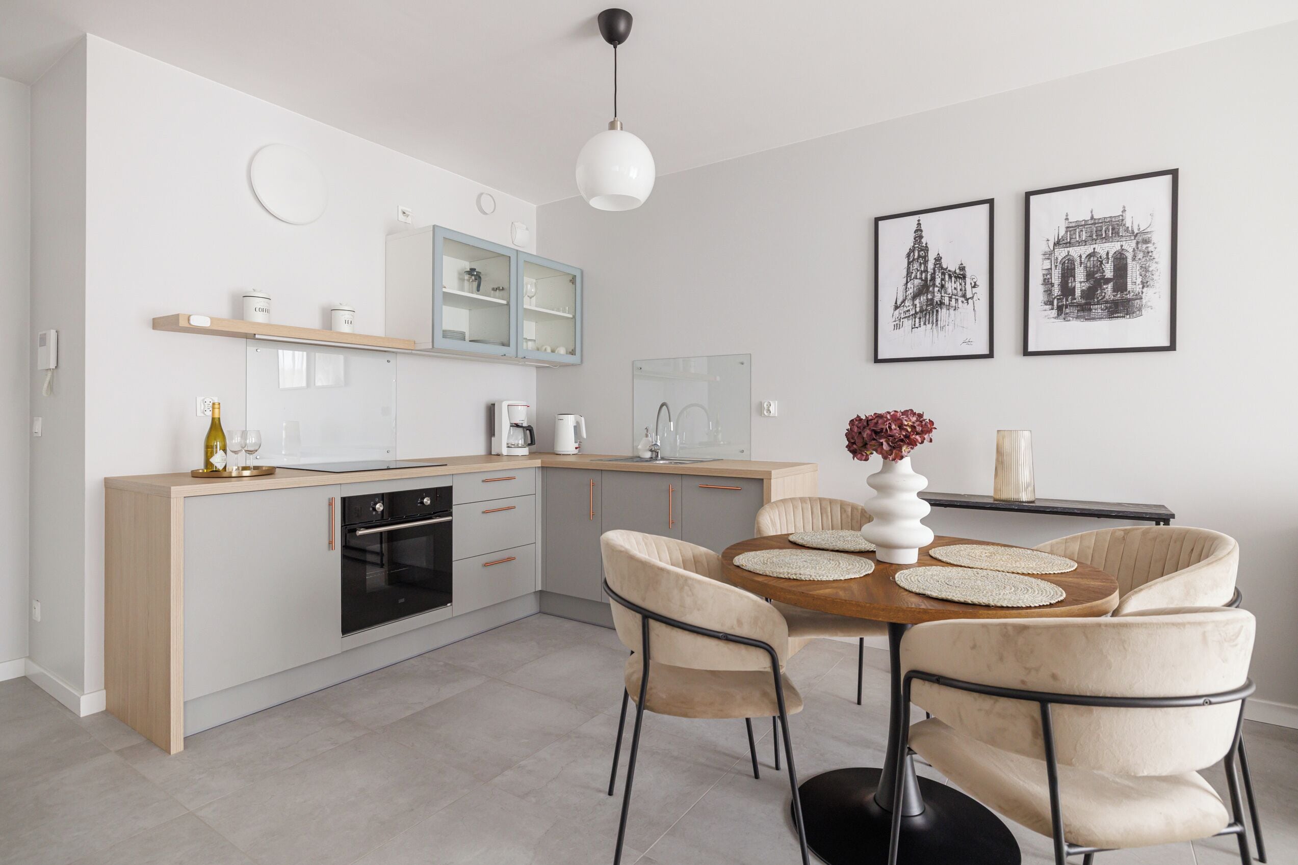 Una cucina moderna con piano di lavoro in legno, forno integrato e zona pranzo con tavolo rotondo e sedie imbottite.