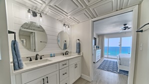 Une salle de bain moderne dotée d’un grand miroir, de deux vasques et d’un dressing.