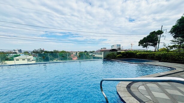 A swimming pool with clear blue water, surrounded by a tiled deck and a metal railing. - Peaceful & Private Hideout (Iloilo)