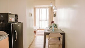 A compact kitchen with a refrigerator, microwave, and a dining area with a table and chairs. - Peaceful & Private Hideout (Iloilo)