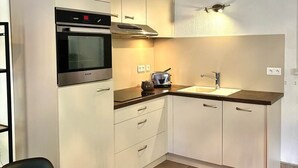 Una cocina compacta con horno empotrado, tostadora y lavamanos.
