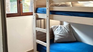 Una cama individual en un dormitorio con ventana, cortina y vistas al exterior.
