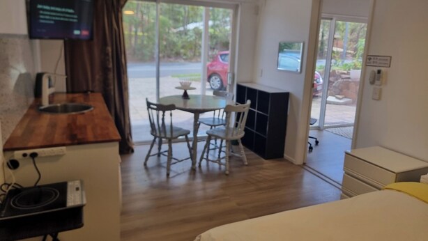A compact hotel room with a kitchenette, a dining area with a table and chairs, and a large window providing a view of the outdoors. - Mountain Creek Retreat (Mountain Creek)