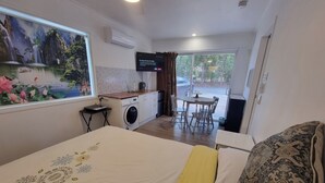 A hotel room with a bed, a small kitchenette, a dining area, and a view of the outside. - Mountain Creek Retreat (Mountain Creek)