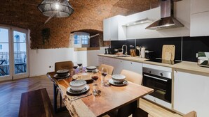 Una cucina moderna con una parete in mattoni, un tavolo da pranzo apparecchiato e un grande forno.