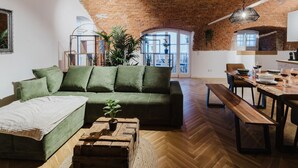 Un accogliente soggiorno con un divano verde, un tavolino in legno e una zona pranzo con una panca e un tavolo in legno.