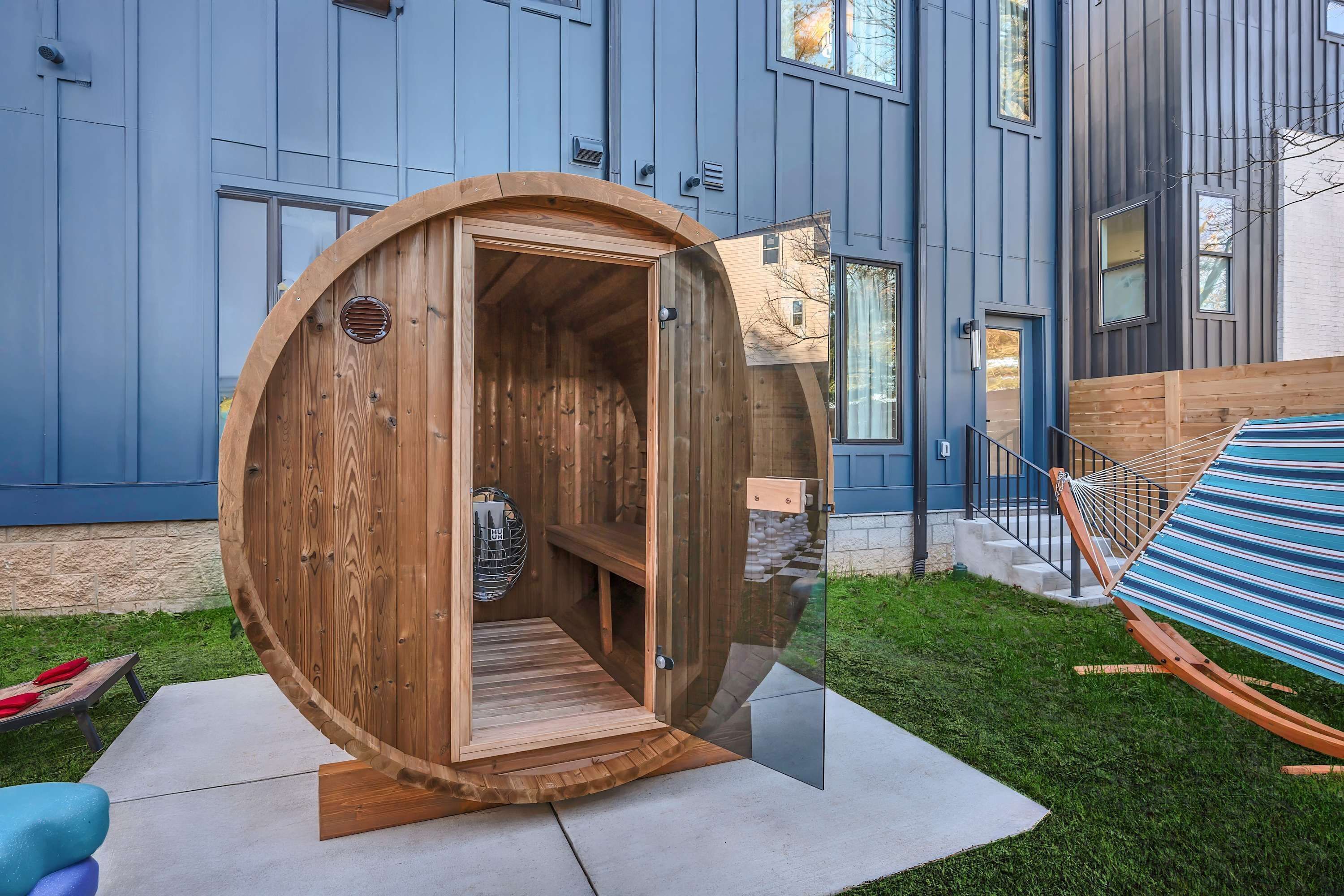 Eine Holzsauna mit Glastür, einer Hängematte und einer Beton-Terrasse.