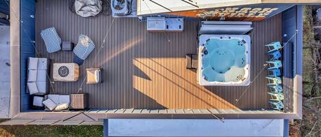 A deck with a hot tub, lounge chairs, and a covered seating area.