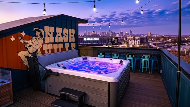Un bar en la azotea con jacuzzi, asientos al aire libre y vistas al horizonte de la ciudad.