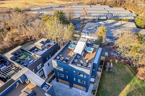 Un bâtiment moderne à plusieurs étages, doté de terrasses sur le toit et d’une piscine.