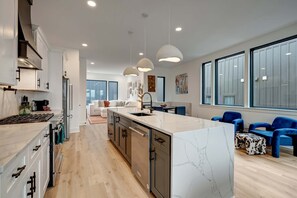 A modern kitchen with a central island, built-in appliances, and pendant lighting. - Twin Homes Hot Tub Rooftop Game Zone at Nashville (Nashville)