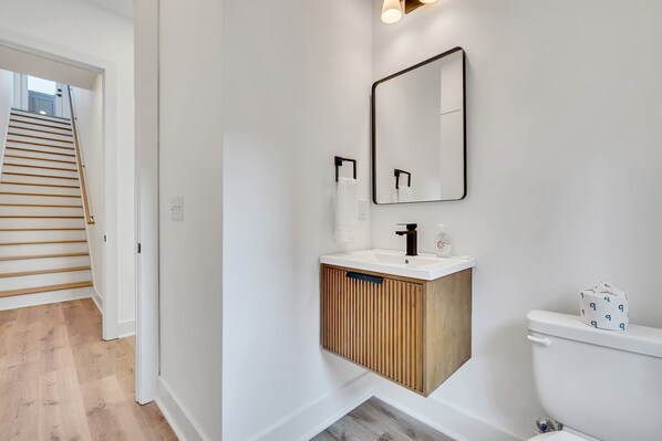 A modern bathroom with a wooden vanity, white sink, and a large mirror.