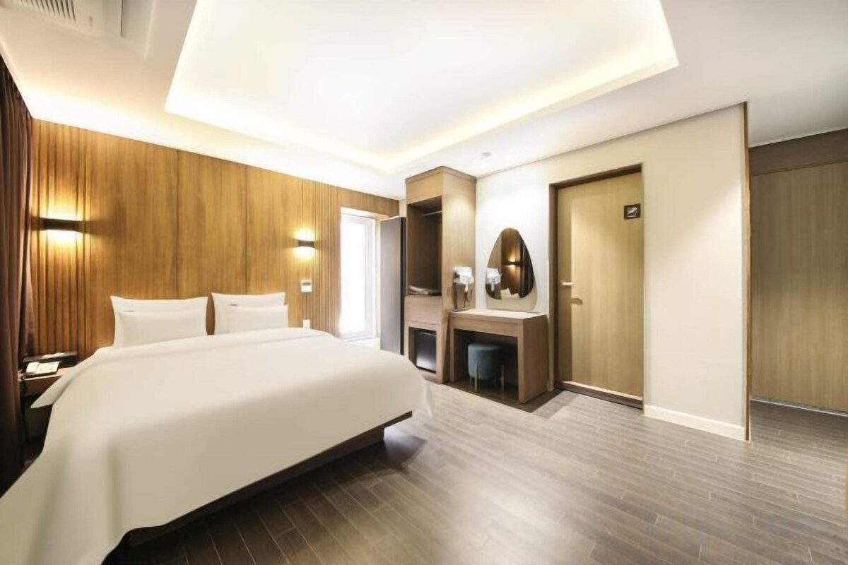 Habitación de hotel con una cama grande, mesitas de noche, un espejo, un escritorio y un armario.
