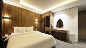 A modern hotel room with a large bed, wooden paneling on the walls, a vanity with a mirror, and a small trash bin. - Jeonju Hotel Twosome Stay Seosin (Jeonju)