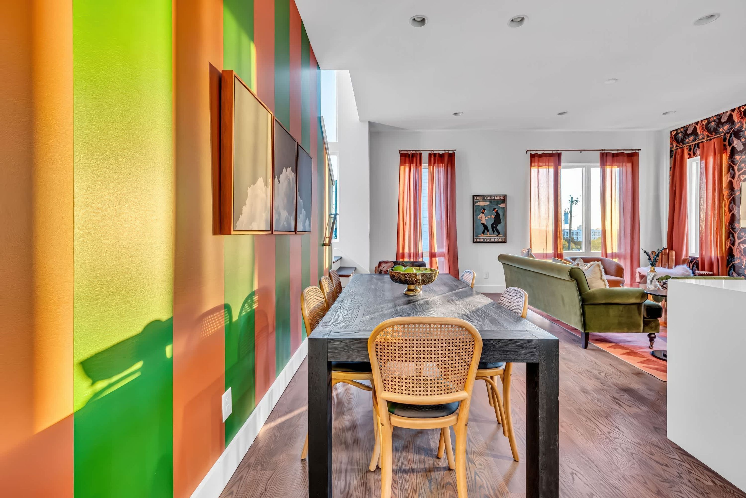 A dining area with a wooden table, wicker chairs, and a green sofa.