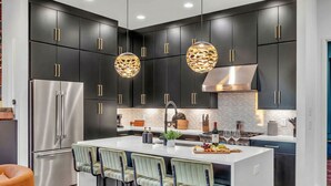 A modern kitchen with dark cabinets, stainless steel appliances, and a central island with bar stools. - Disco Lounge Double Rooftop Hot Tub Nashville (Nashville)