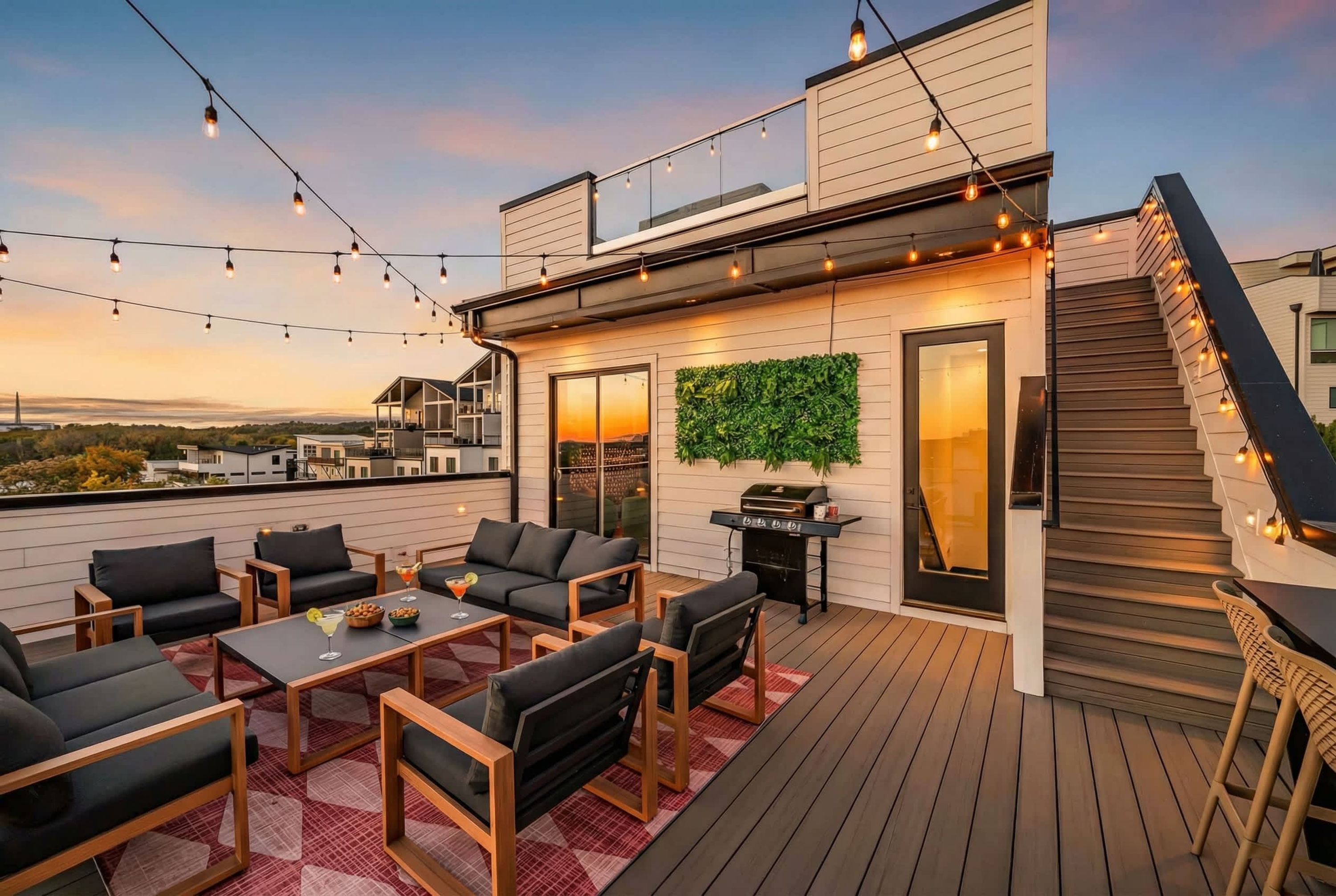A rooftop patio with outdoor seating, a grill, and string lights.