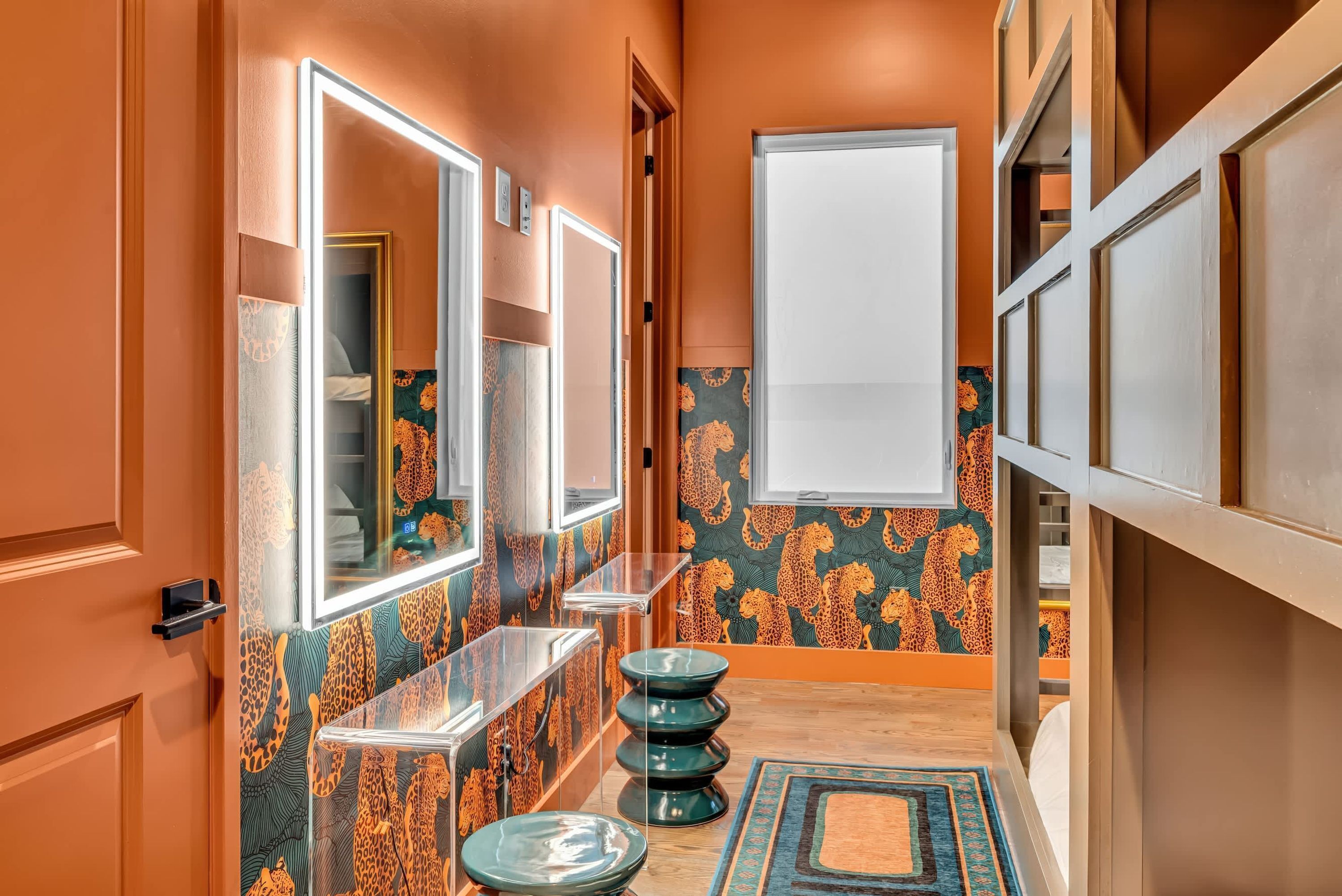 A narrow hallway with a mirror, a vanity, and a toilet. The walls are decorated with a leopard print pattern.