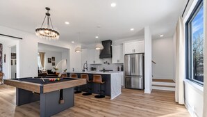 Cozinha moderna com mesa de bilhar, banquetas de bar e uma ilha grande.
