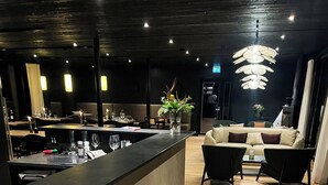 A hotel reception area with a modern design, featuring a reception desk labeled "SILVER BRIDGE," a seating area with sofas, and a wooden floor. - Silver Birch Resort (Rovaniemi)