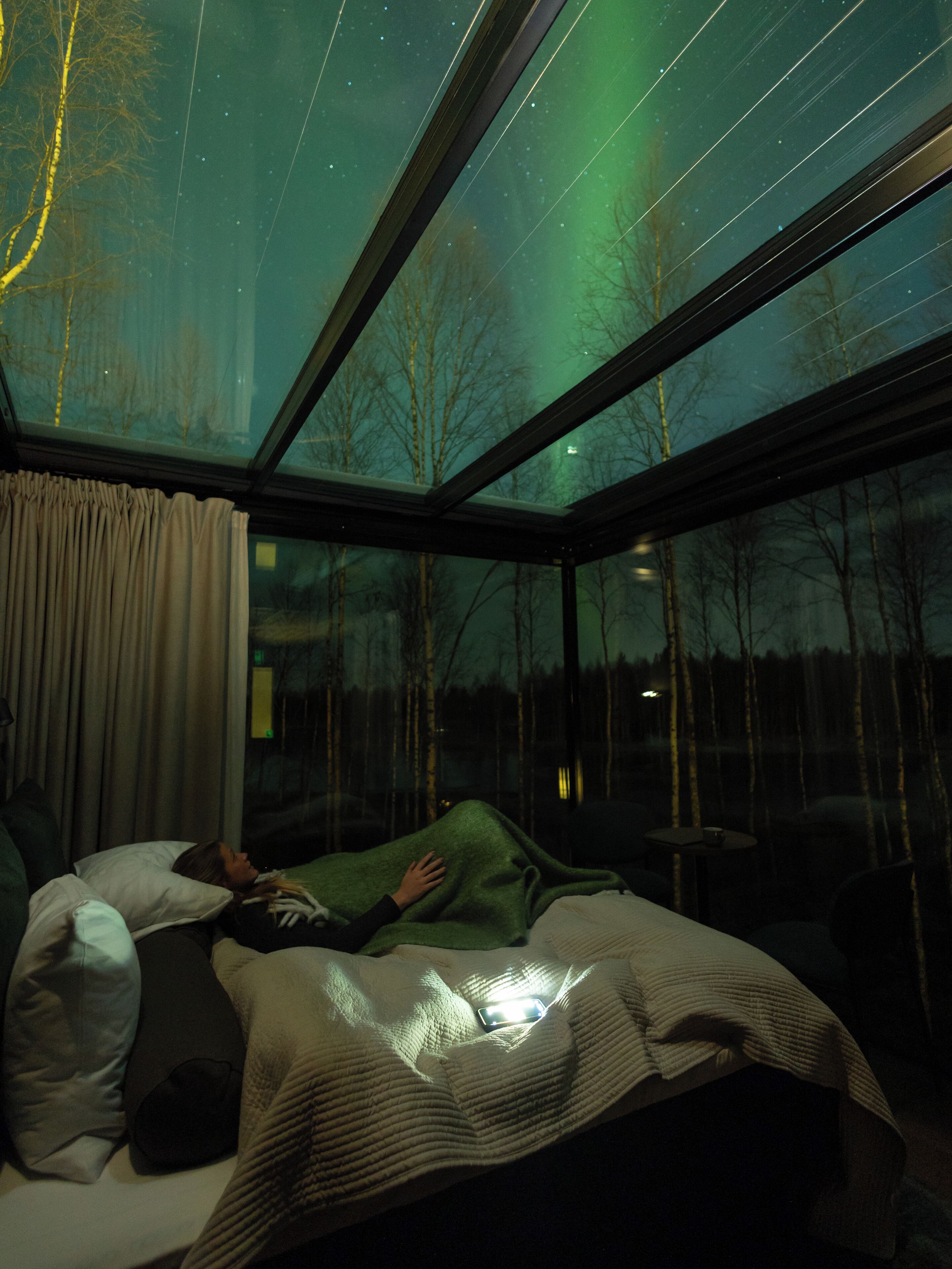 Ein Schlafzimmer mit großem Fenster, einem Bett und einem Nachttisch.