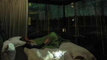 Ein Schlafzimmer mit großem Fenster, einem Bett und einem Nachttisch.