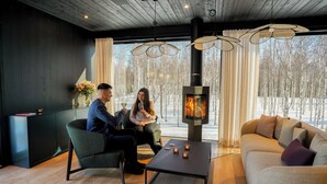 A modern living room with a fireplace, a sofa, and a coffee table. - Silver Birch Resort (Rovaniemi)