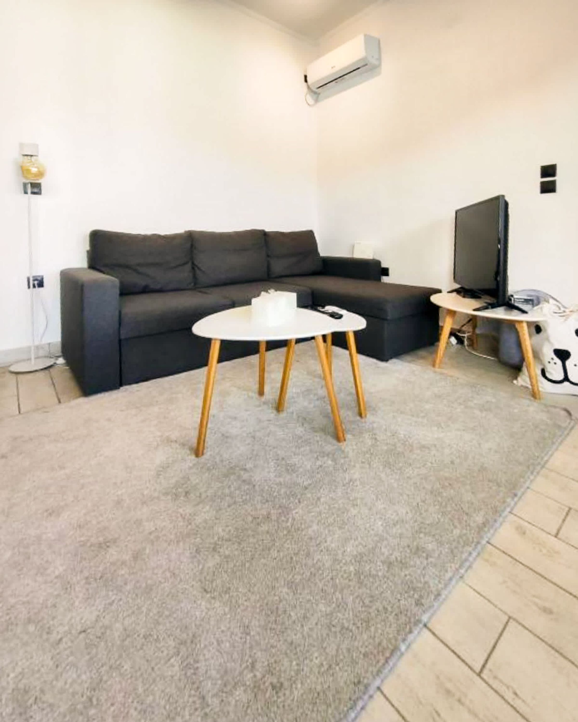 A modern living room with a grey sofa, a round coffee table, and a flat-screen TV.