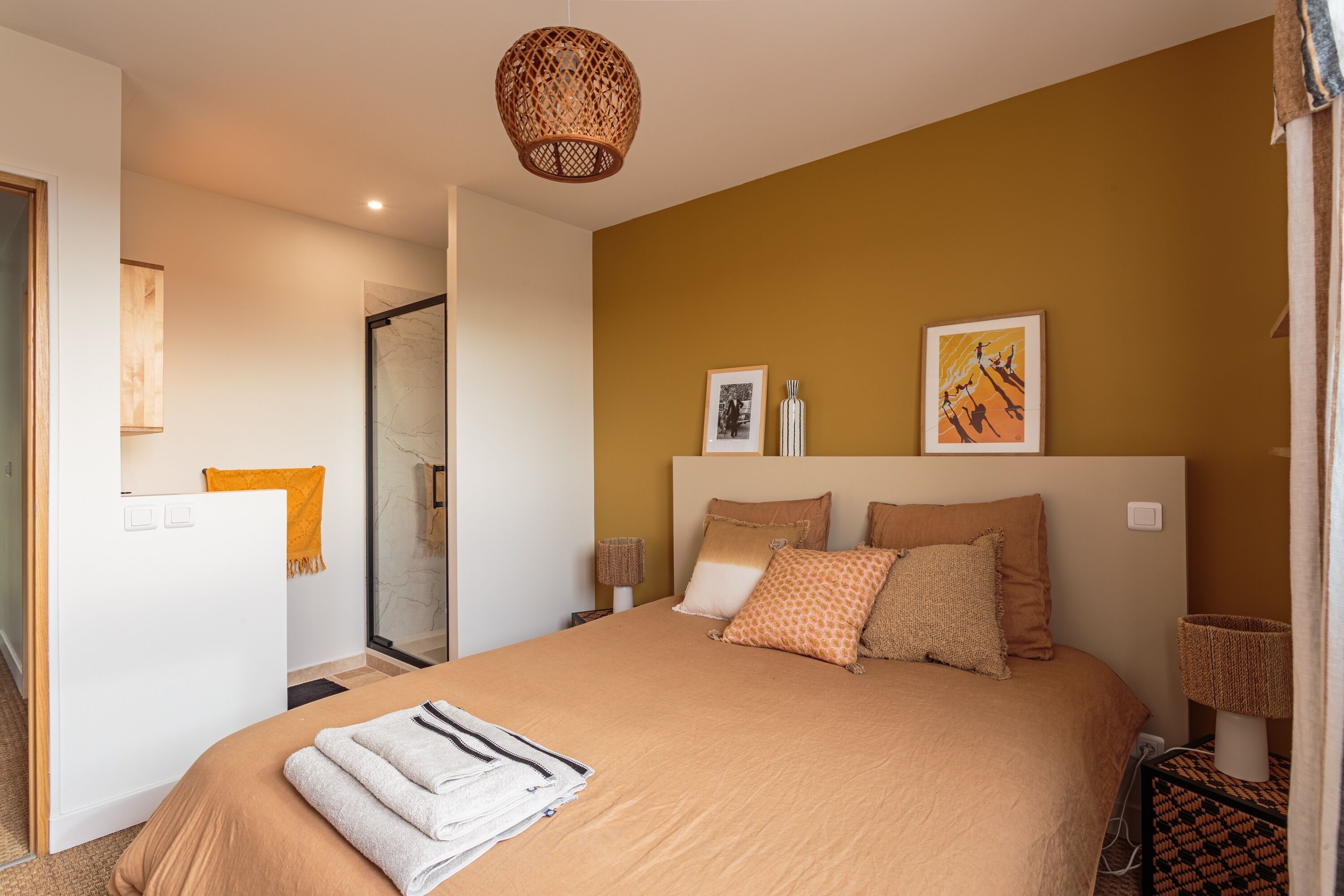 Een slaapkamer met een groot bed, een nachtkastje met een lamp en een deur naar een badkamer.