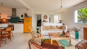 Eine moderne Küche mit einem gelben Kühlschrank, ein Essbereich mit Holzkästen, ein weißes Sofa und ein Couchtisch.