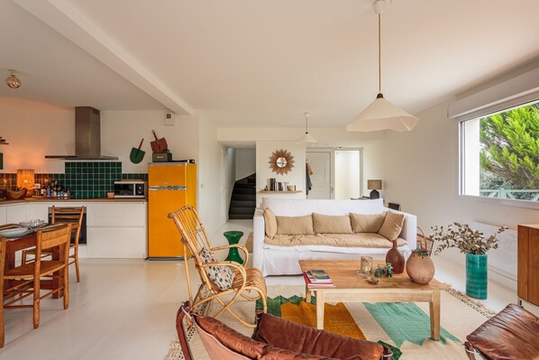 A modern kitchen with a yellow refrigerator, dining area with wooden chairs, a white sofa, and a coffee table. - Amaya - A 10min de la Plage (Anglet)