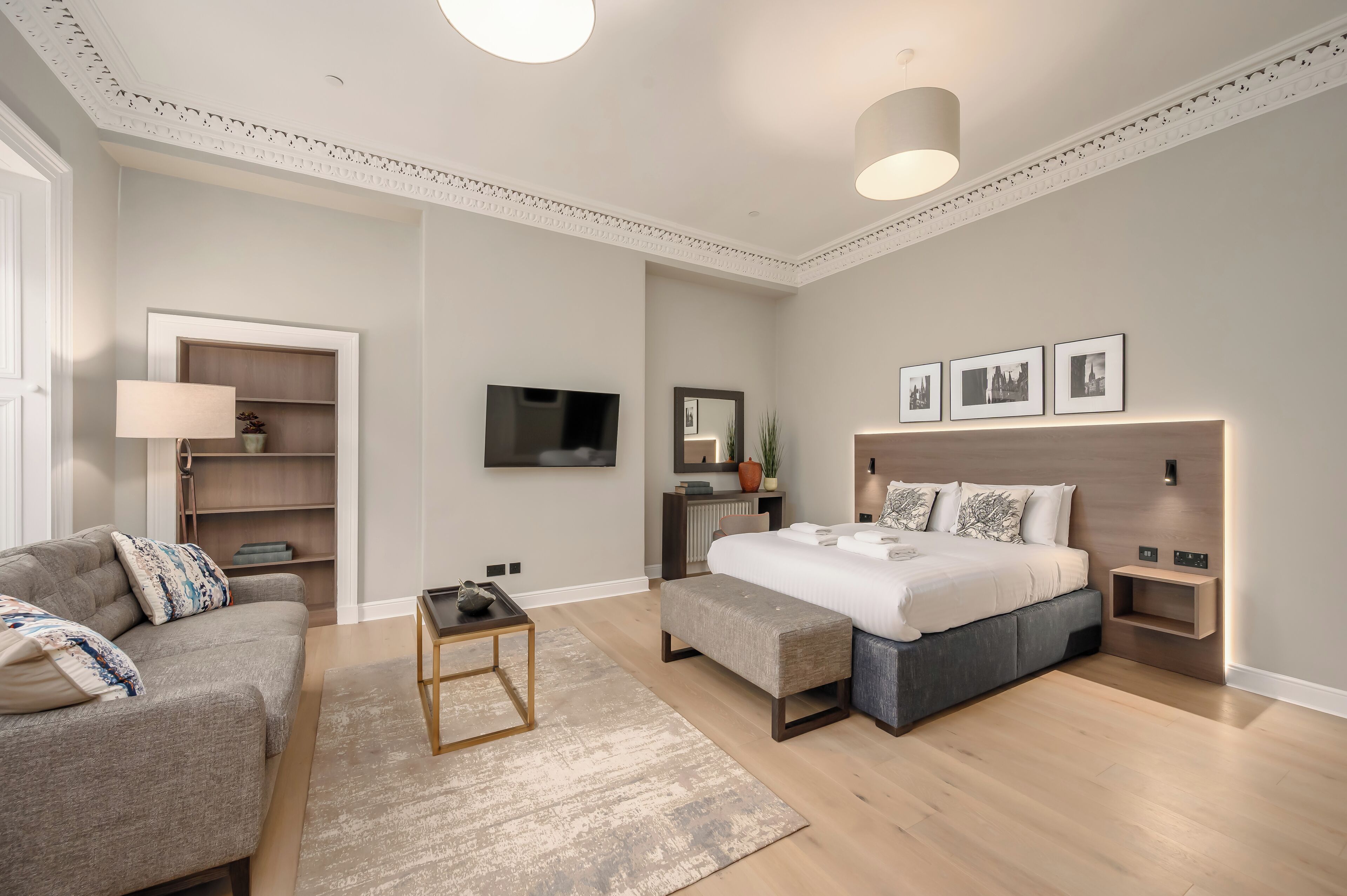 A modern bedroom with a bed, bedside tables, a TV, and a bookshelf.