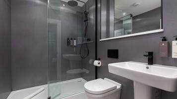 A modern bathroom with a glass-enclosed shower, a white sink, and a toilet.