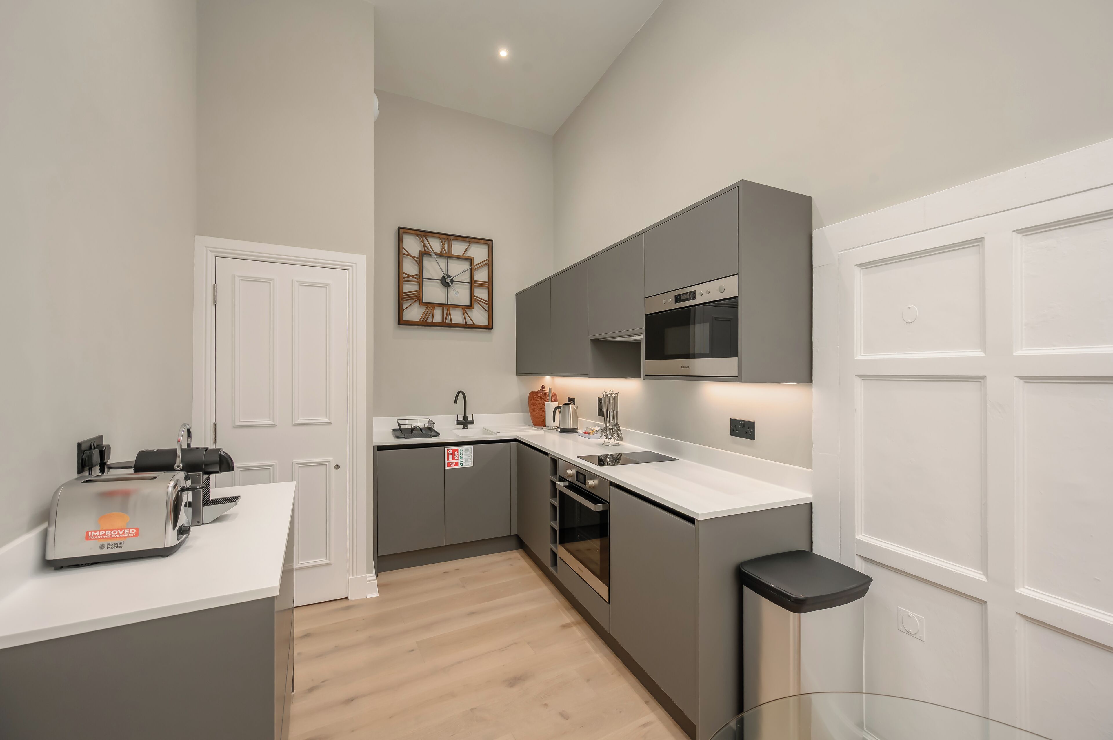 A modern kitchen with grey cabinetry, a built-in oven, and a microwave.