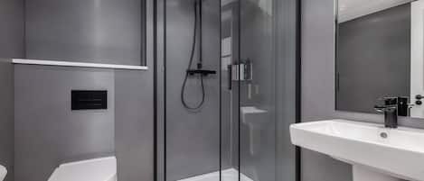 Une salle de bain moderne avec une douche à parois de verre, des toilettes blanches et un grand lavabo.