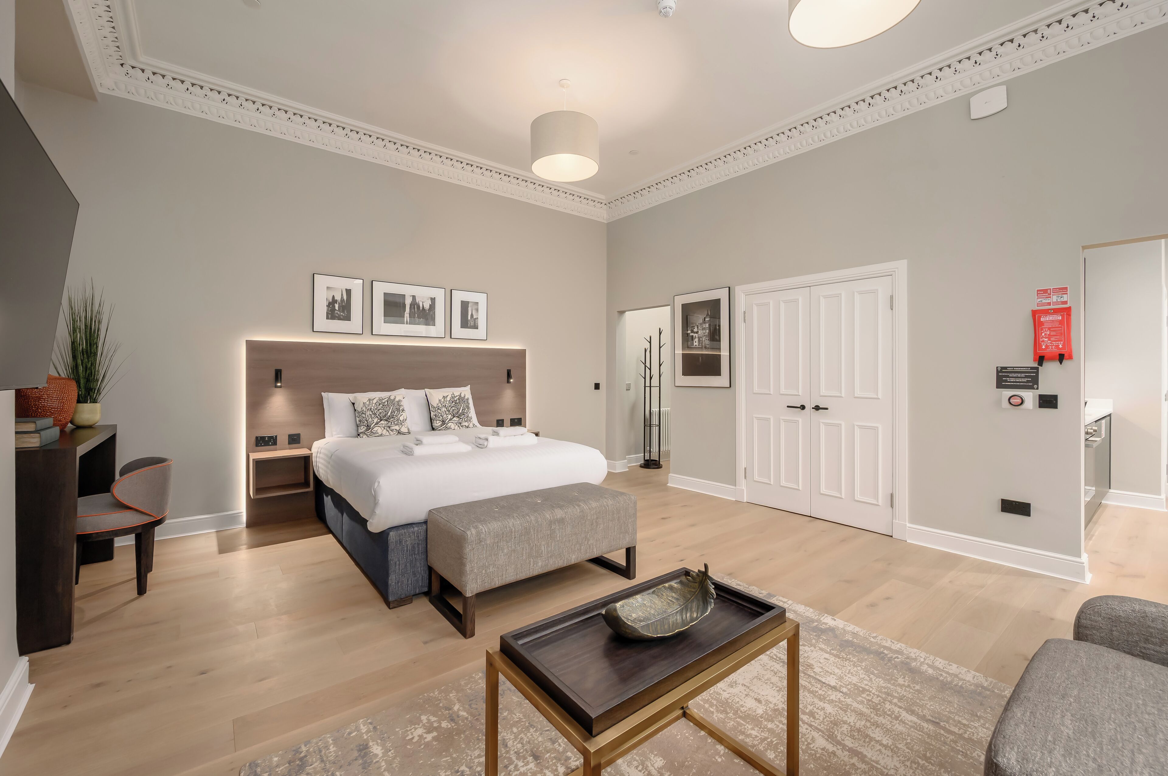 A modern bedroom with a large bed, bedside tables, a bench, and a coffee table.