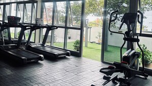 Un gimnasio con cintas de correr, una bicicleta estática y una máquina de remo.