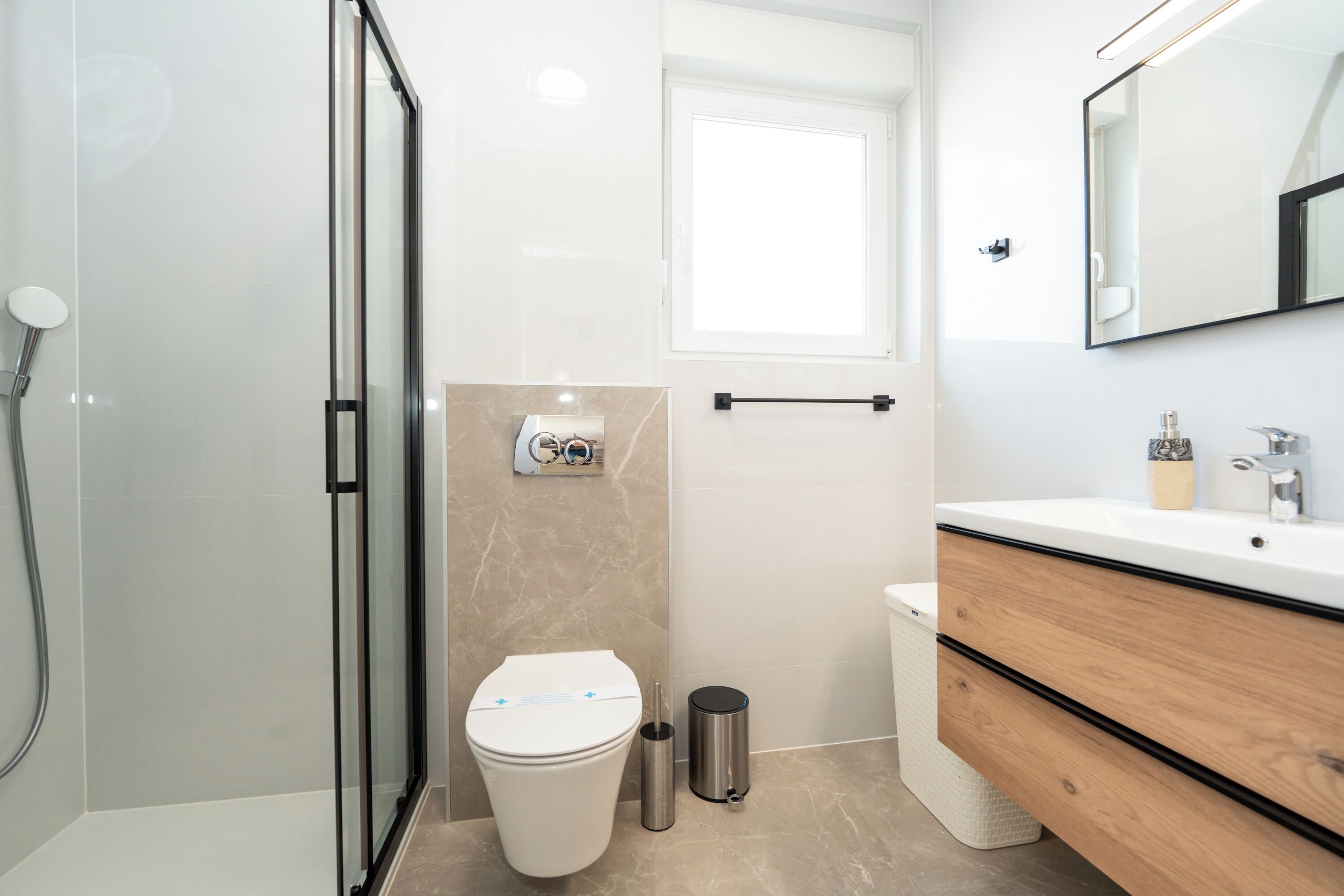 Une salle de bain moderne dotée d’une douche à parois de verre, de toilettes, d’un bidet et d’un meuble-lavabo avec un miroir.