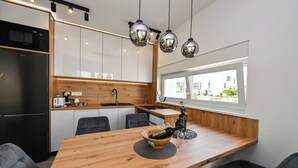 A modern kitchen with a wooden island, black appliances, and pendant lighting. - Nova Luxury Residence apartment with private heated pool (Novalja)