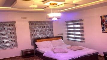 Un dormitorio con cama, decoración de pared estampada, una lámpara de techo y una ventana con persianas.