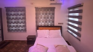 Ein Schlafzimmer mit Bett, Wandgestaltung mit Muster, Klimaanlage und Deckenleuchte.