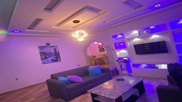 Ein modernes Wohnzimmer mit einer Couch, einem Couchtisch und einem an der Wand befestigten Fernseher.