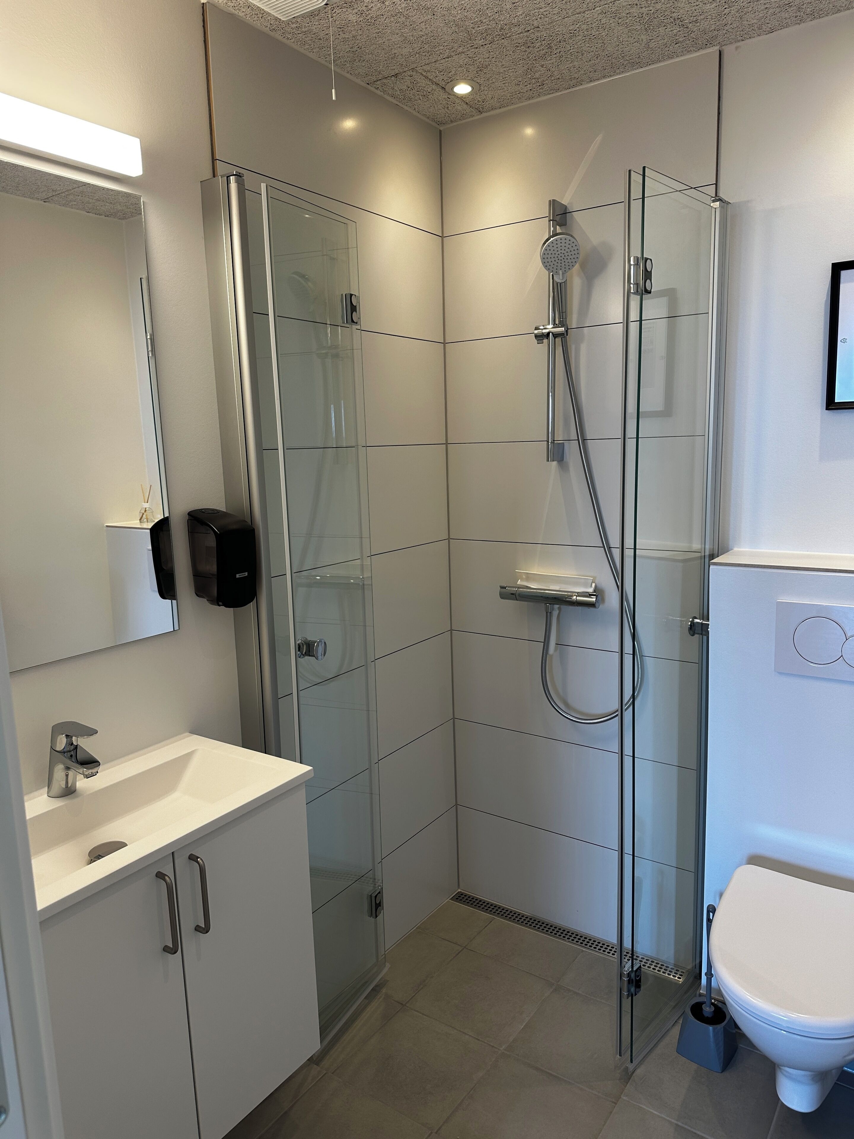 Een moderne badkamer met een douchecabine van glas, een wit wastafelmeubel en een toilet.