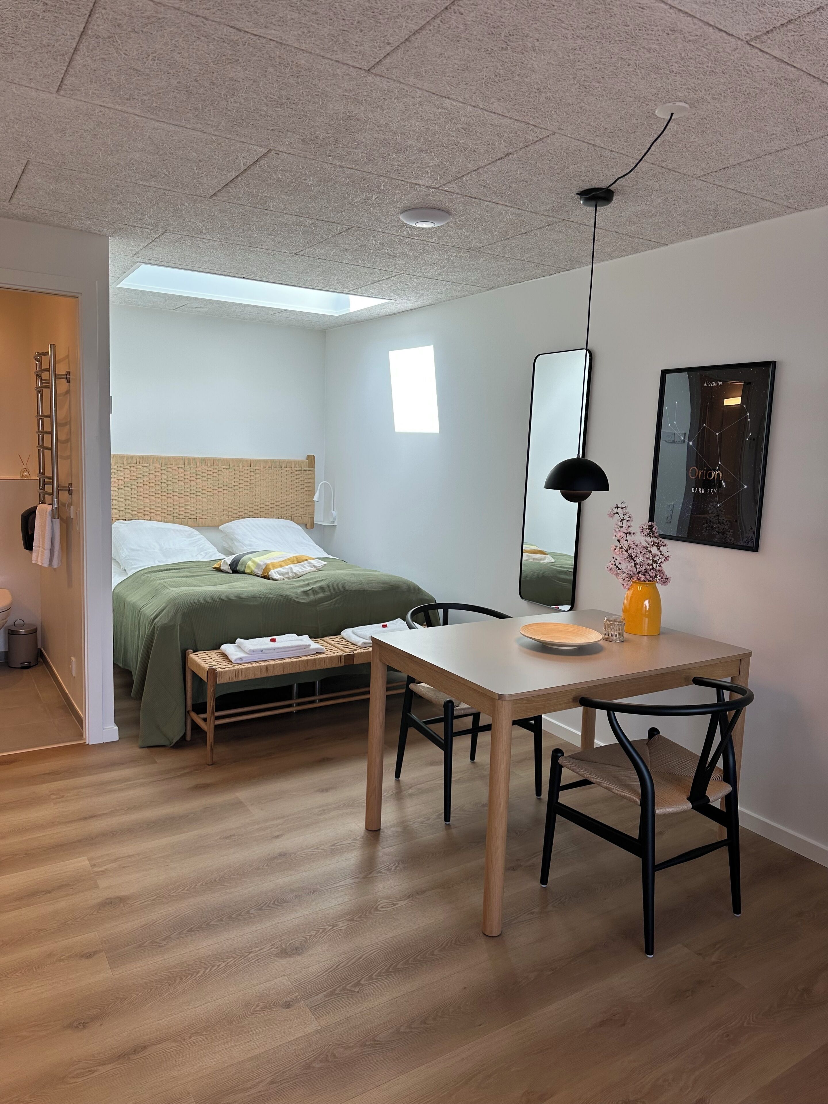 A modern bedroom with a bed, bedside table, lamp, and a framed picture on the wall.